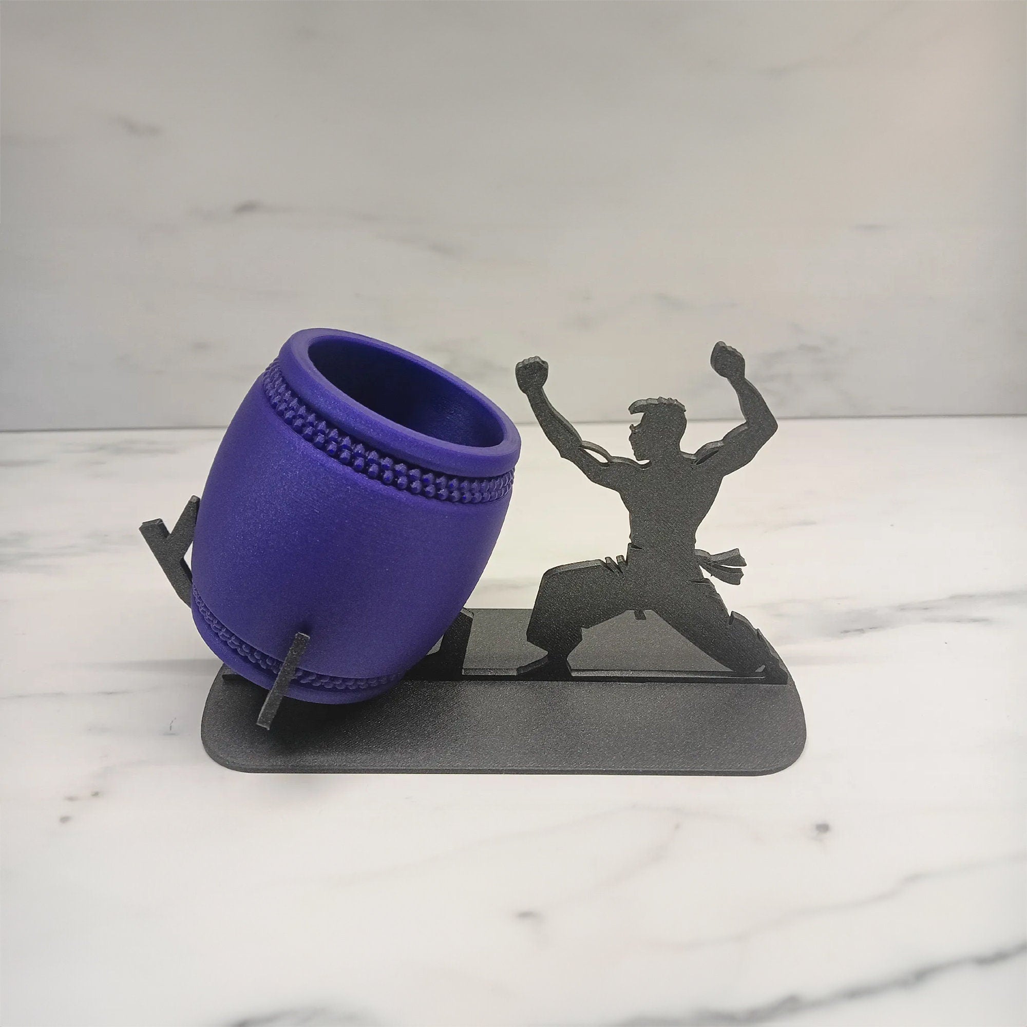 a purple cup sitting on top of a table next to a figurine