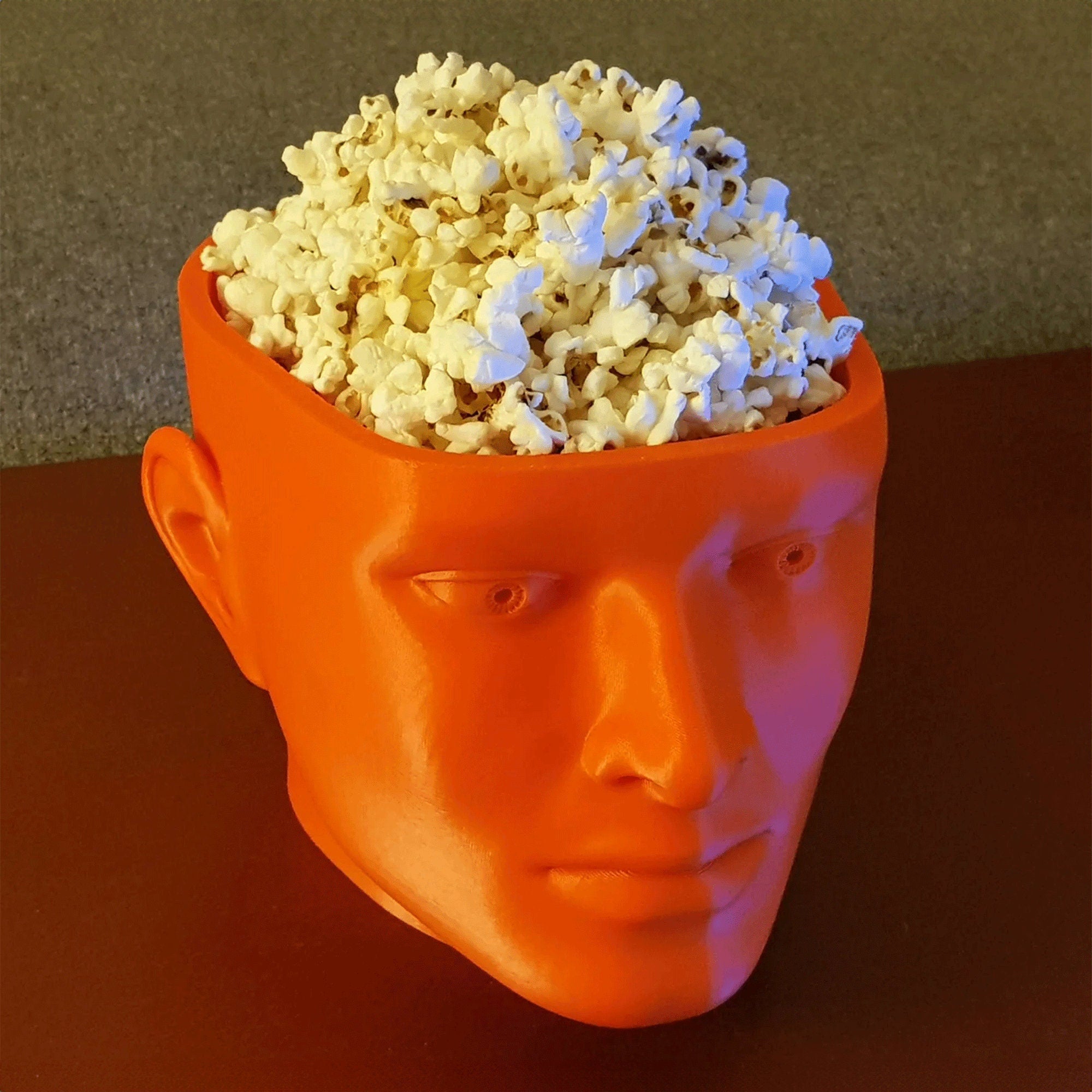 a man's head with a bowl of popcorn on top of it