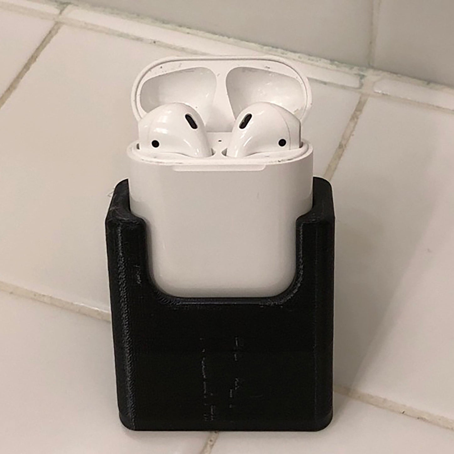 a pair of white airpods sitting on top of a black holder