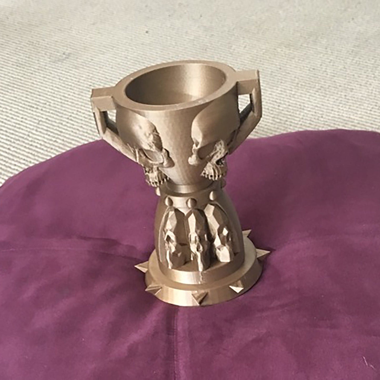 a metal cup sitting on top of a purple cushion