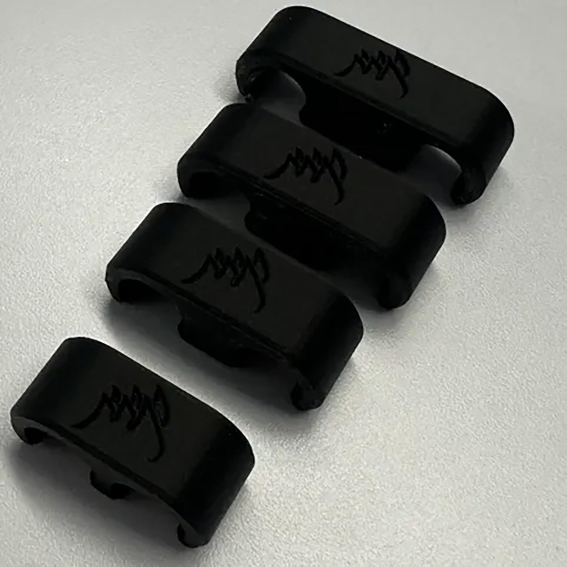 a set of four black plastic clips with writing on them