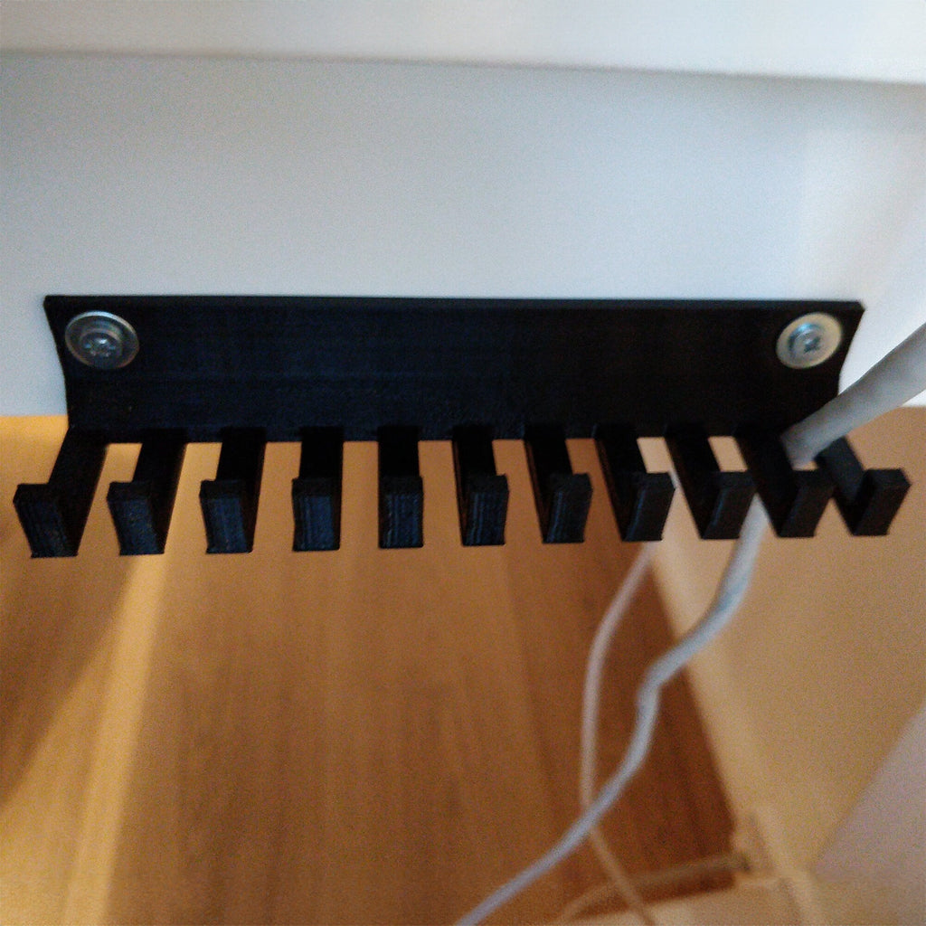 Slotted cable holder organizer docking charging cable ends on a desk edge, view 2