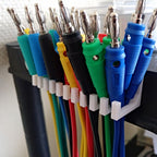 Slotted cable holder organizer docking charging cable ends on a desk edge, view 3