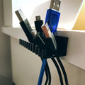 Slotted cable holder organizer docking charging cable ends on a desk edge