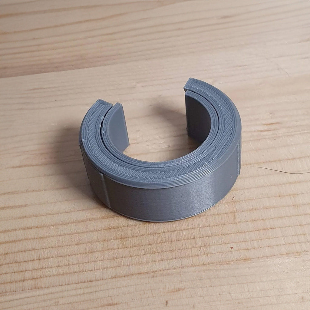 Reusable hex-shaped cable bundling ring snapped around a coiled charging cord, view 2