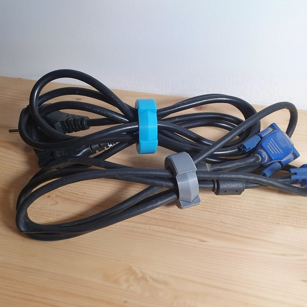 Reusable hex-shaped cable bundling ring snapped around a coiled charging cord
