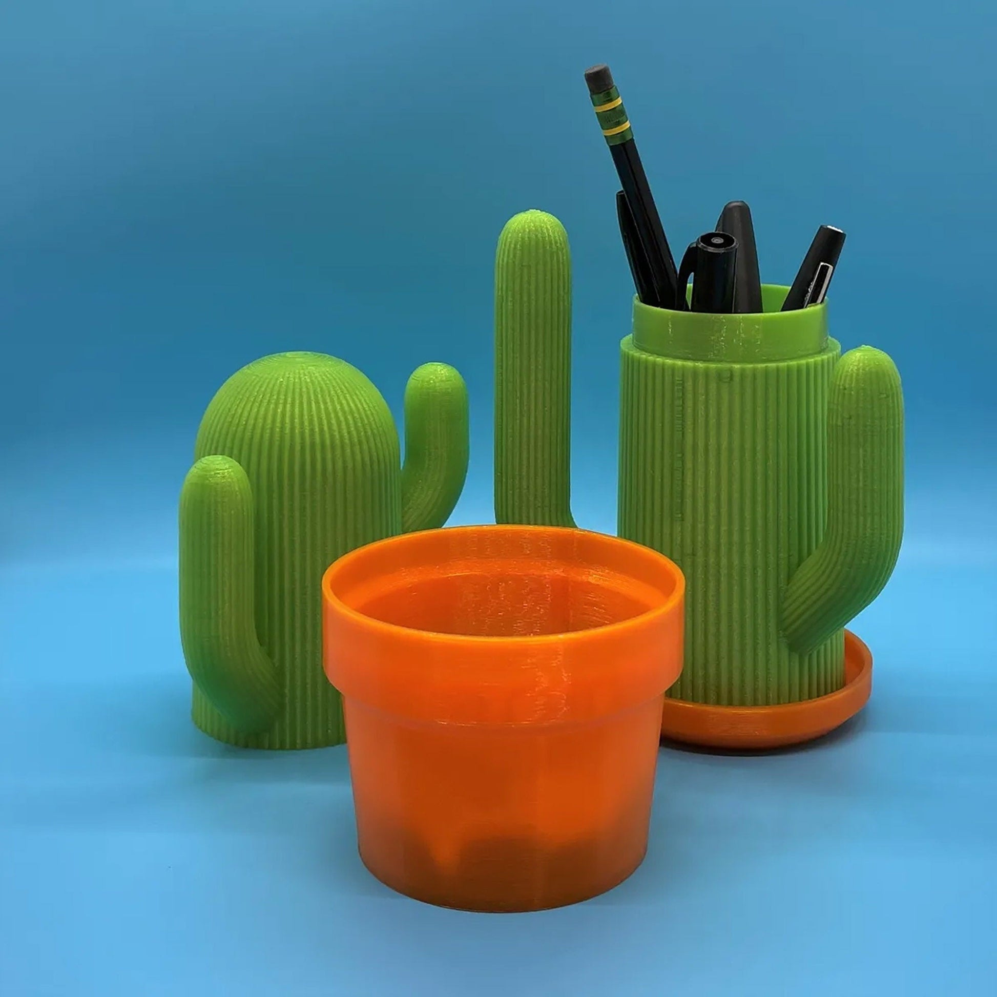 a green cactus with two orange cups and a pen holder