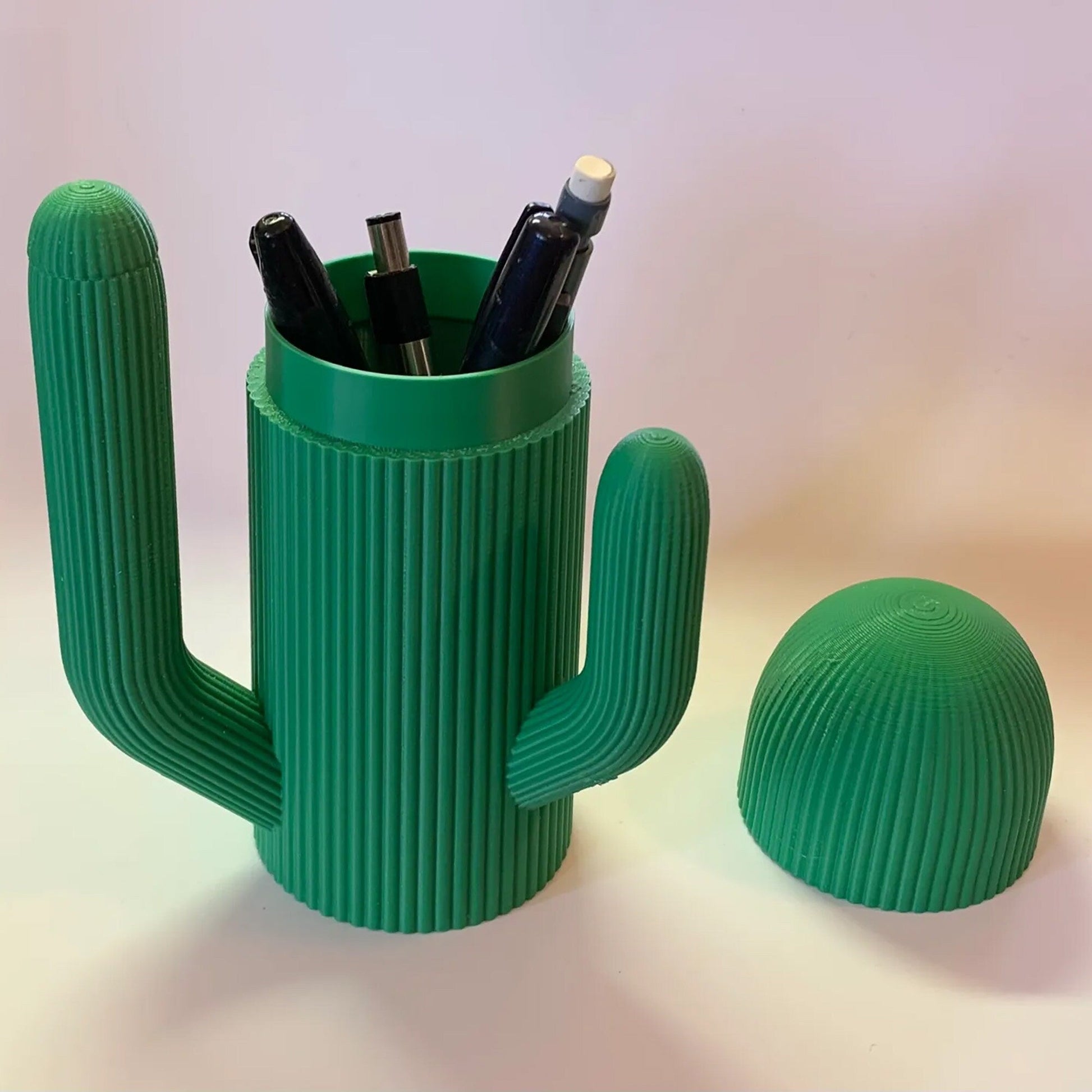 a green cactus shaped pen holder next to a green cactus