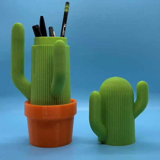 a cactus shaped pen holder next to a cactus plant