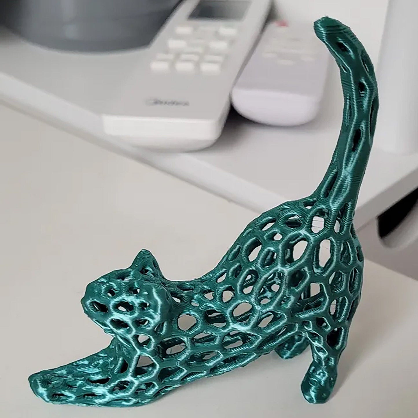 a green cat figurine sitting on top of a desk