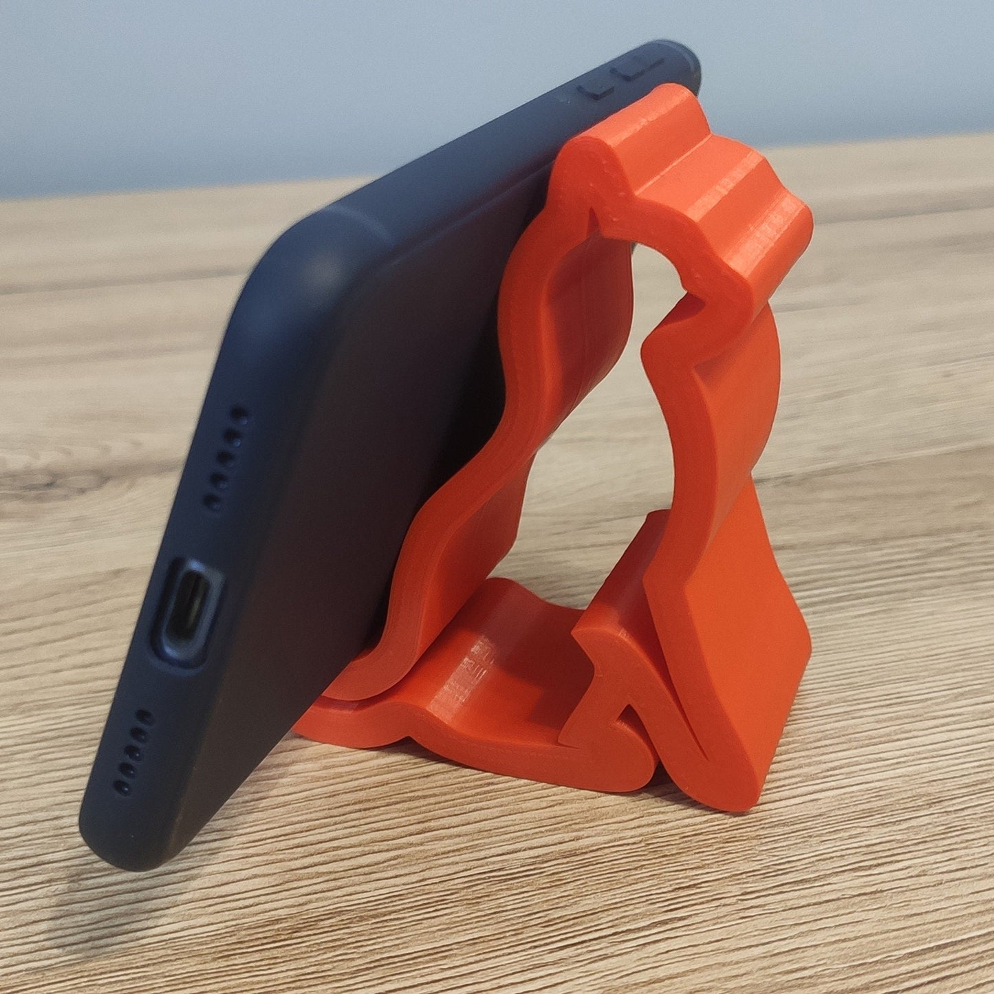 an orange and black cell phone holder on a wooden table