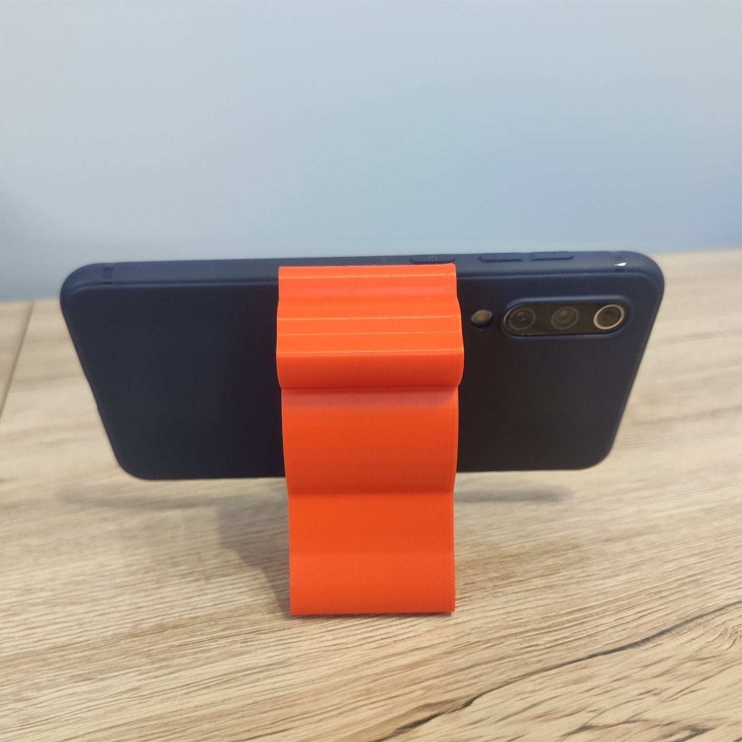 a cell phone with an orange ribbon attached to it