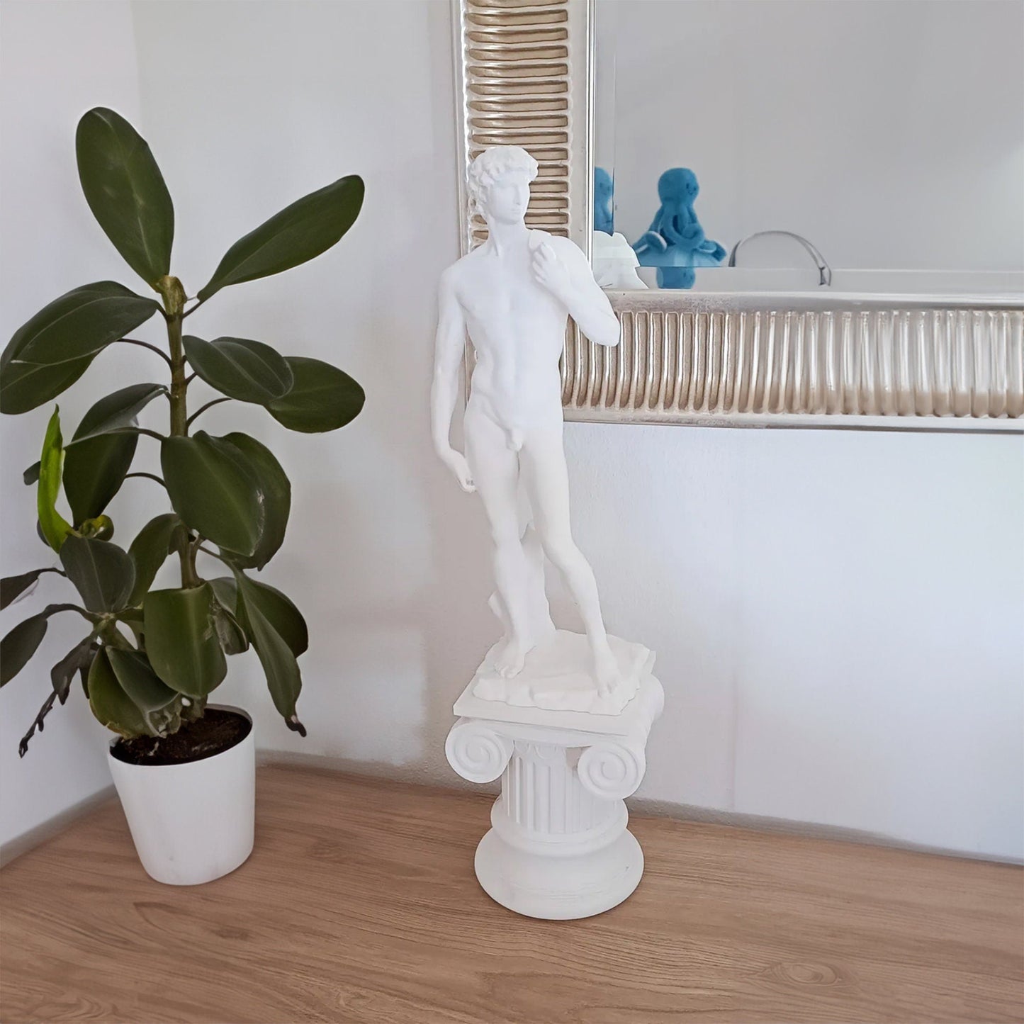 a white statue next to a potted plant on a table