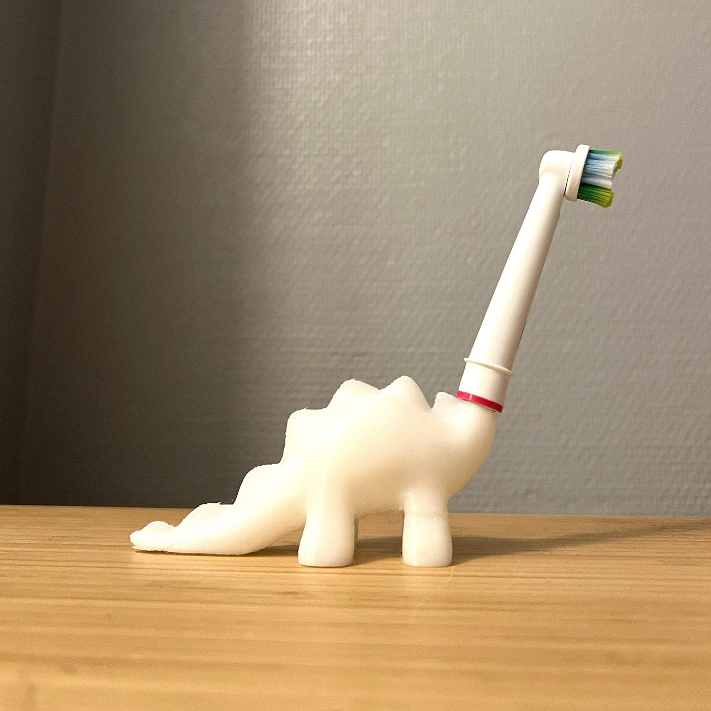 a toothbrush holder shaped like a dinosaur on a table