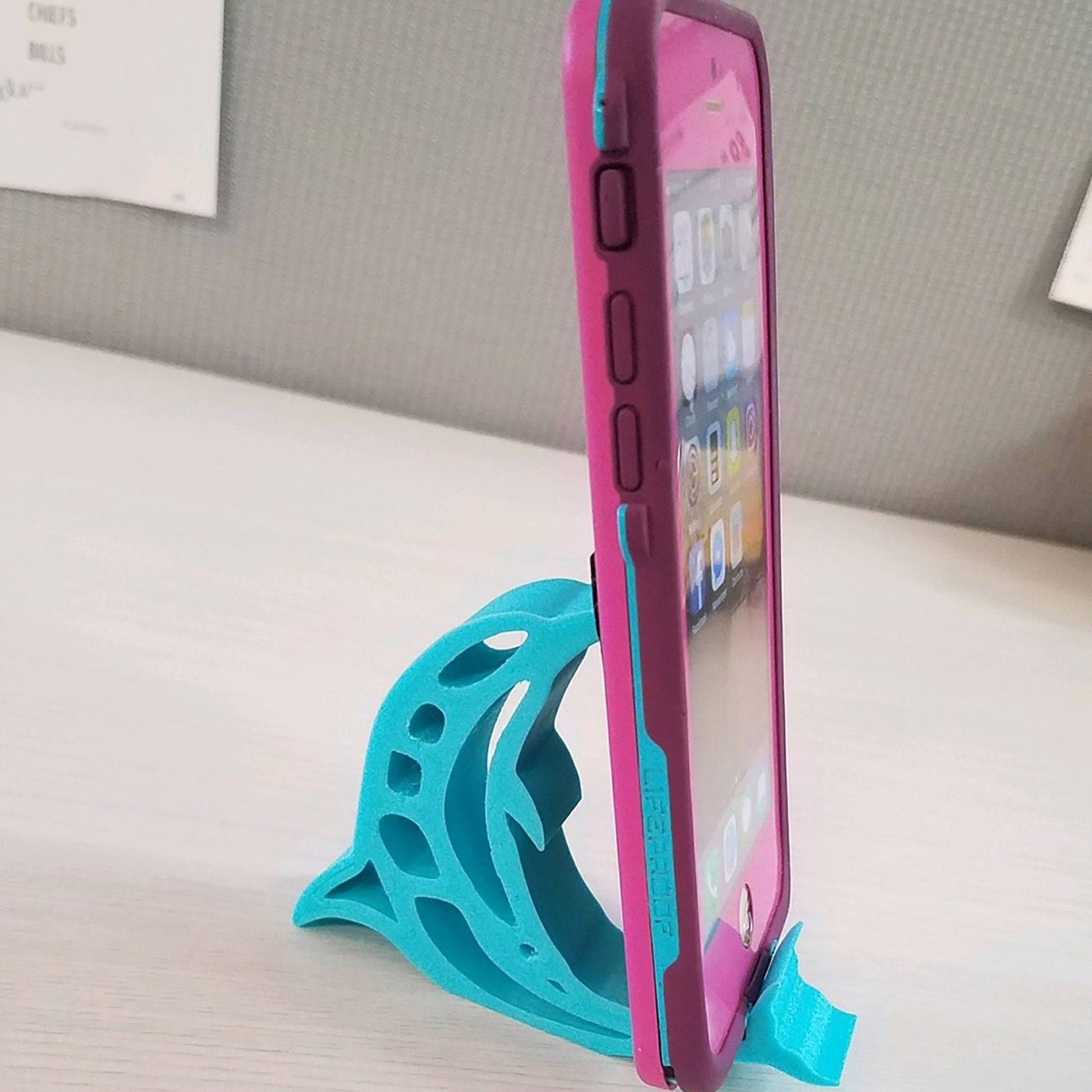 a pink and blue cell phone holder on a table