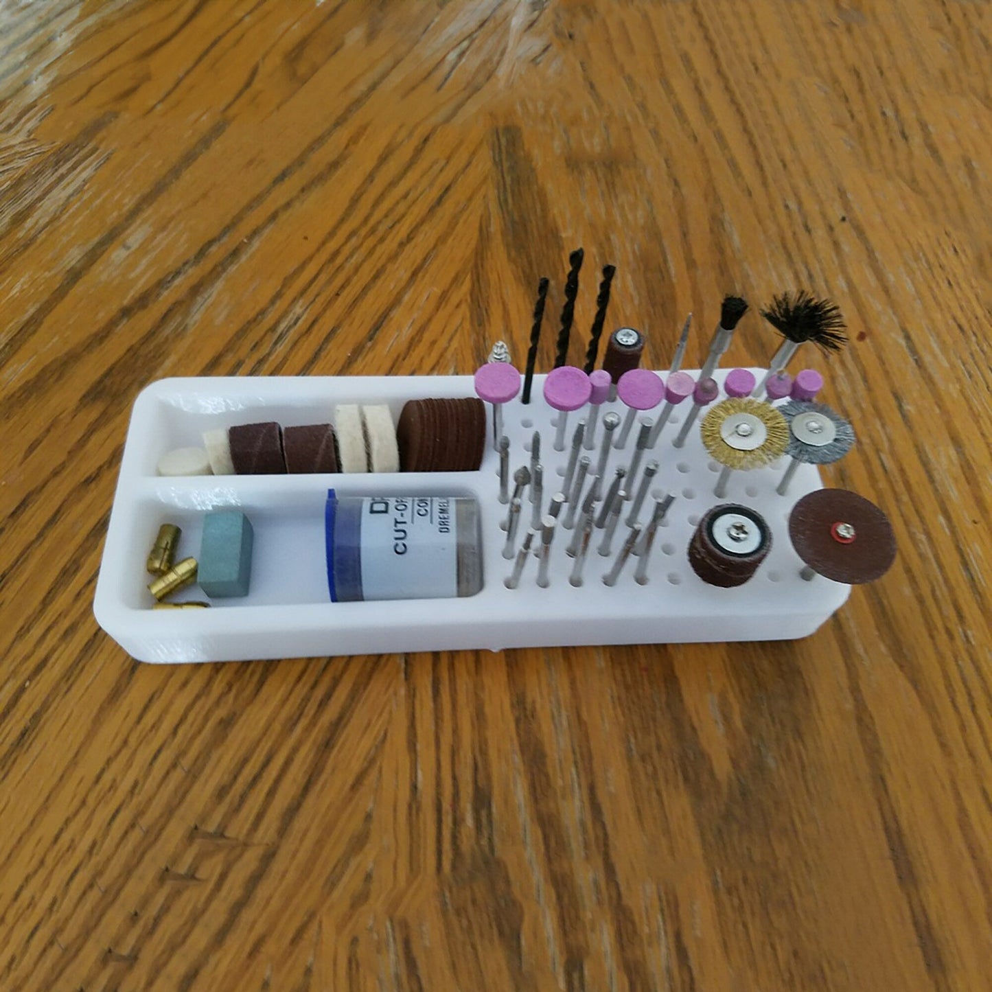 a wooden table topped with a white tray filled with sewing supplies