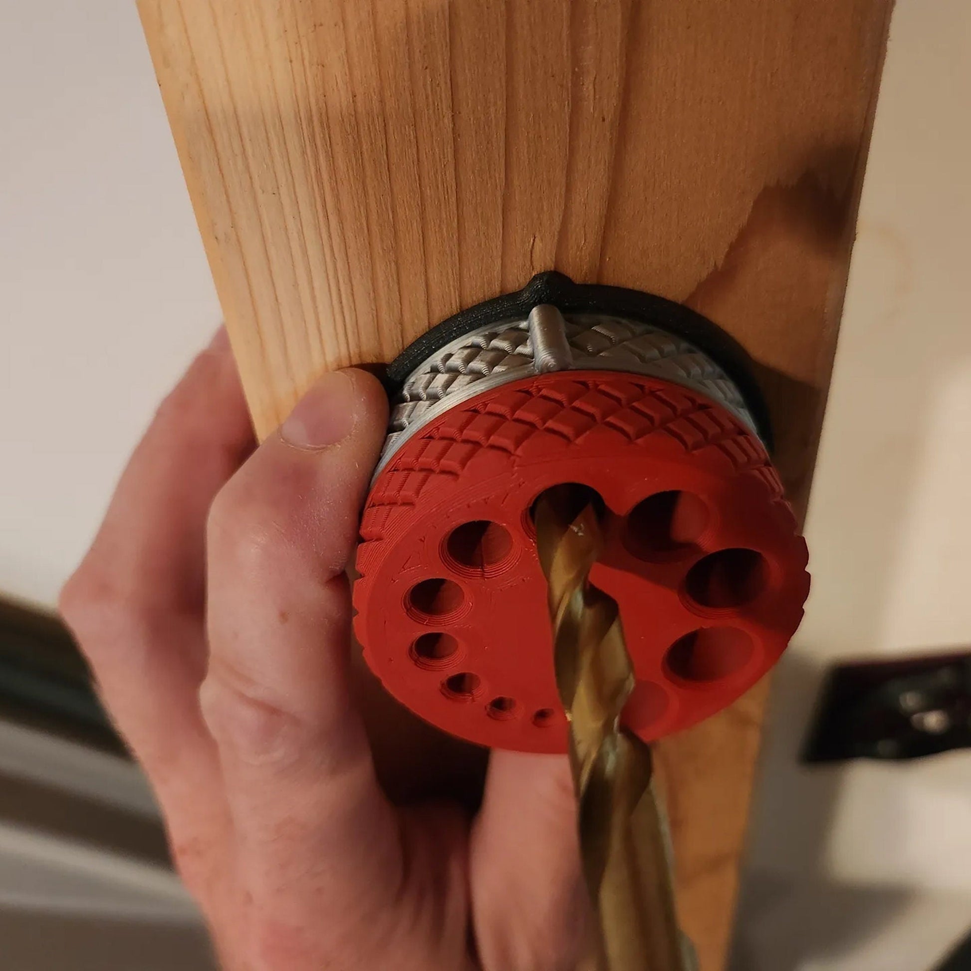 a person holding a piece of wood with a drill bit in it