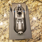Wall mount charging dock holding a spare Dyson V8 to V15 battery and handle