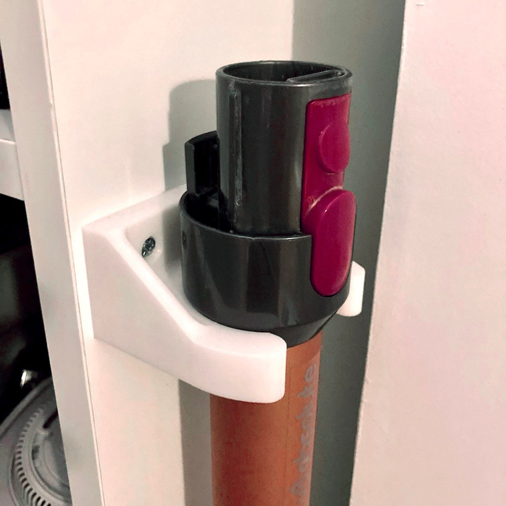 Wall mount wand holder storing a Dyson stick vacuum extension tube upright