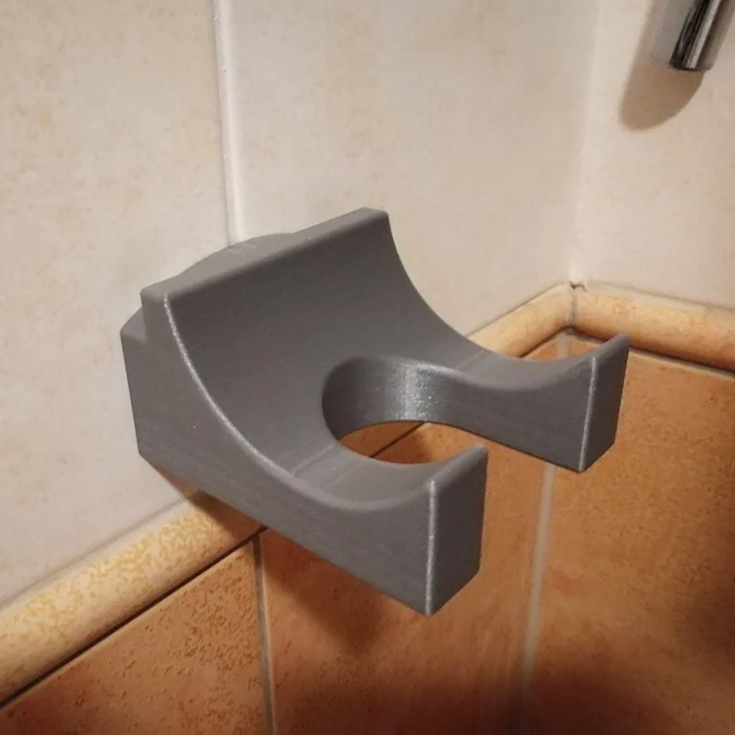 a gray toilet paper dispenser on a tiled wall