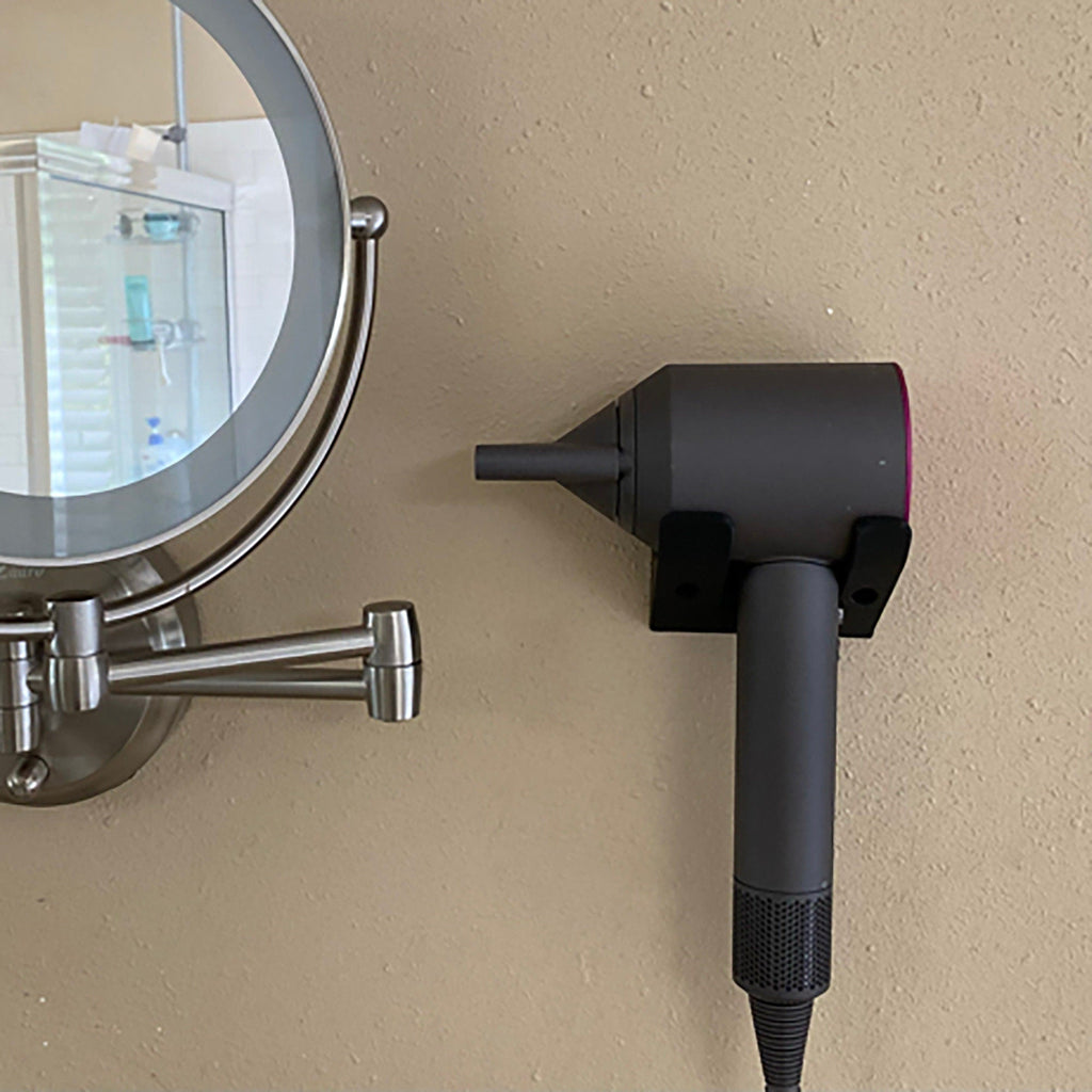Minimalist two-arm wall cradle holding a Dyson Supersonic hair dryer horizontally, view 2