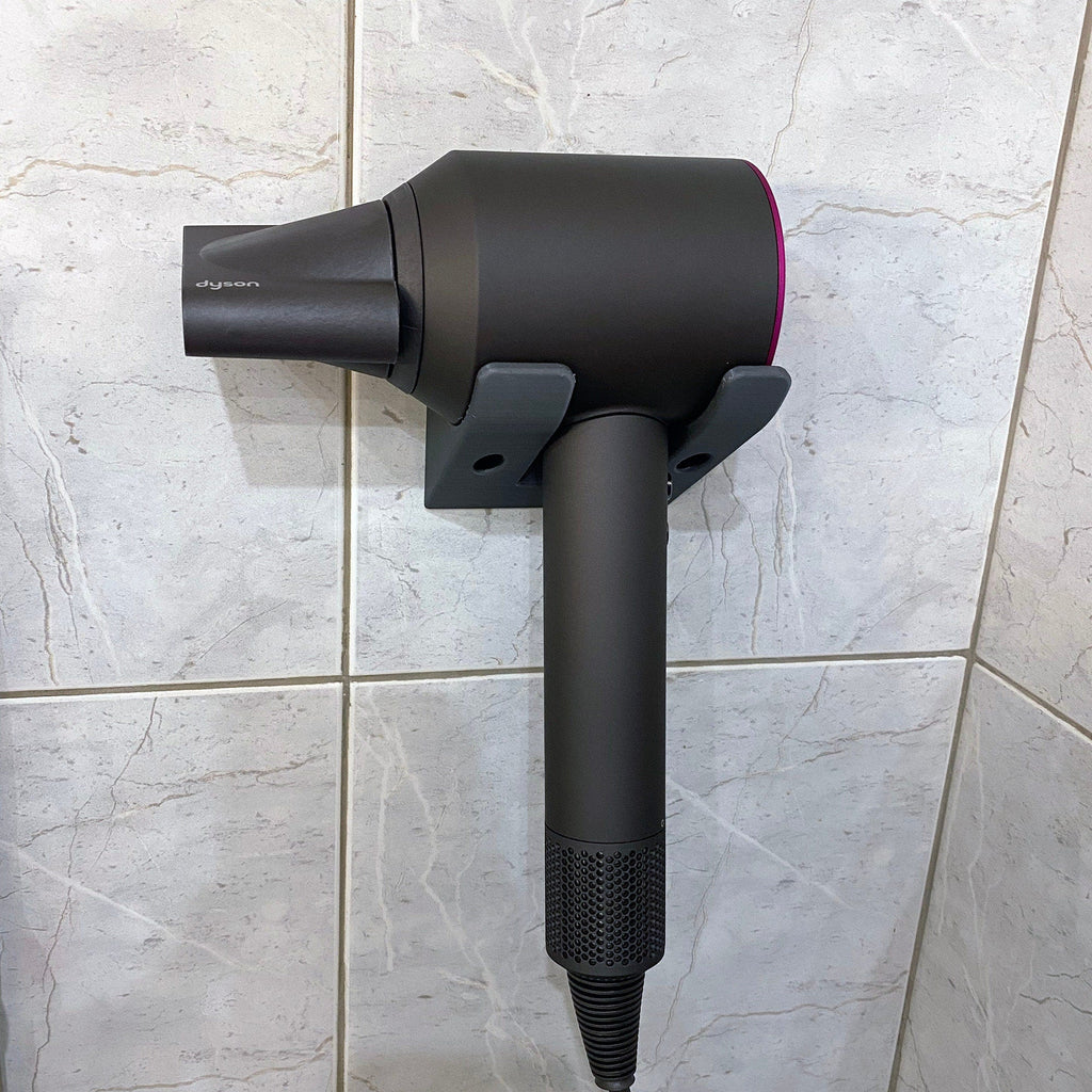 Minimalist two-arm wall cradle holding a Dyson Supersonic hair dryer horizontally