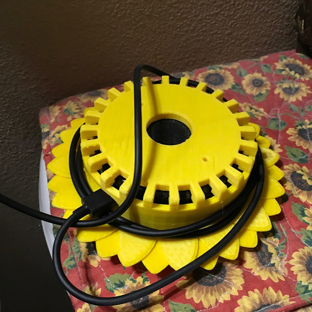 Sunflower stand with layered petals framing a puck-style Echo Dot speaker, view 4