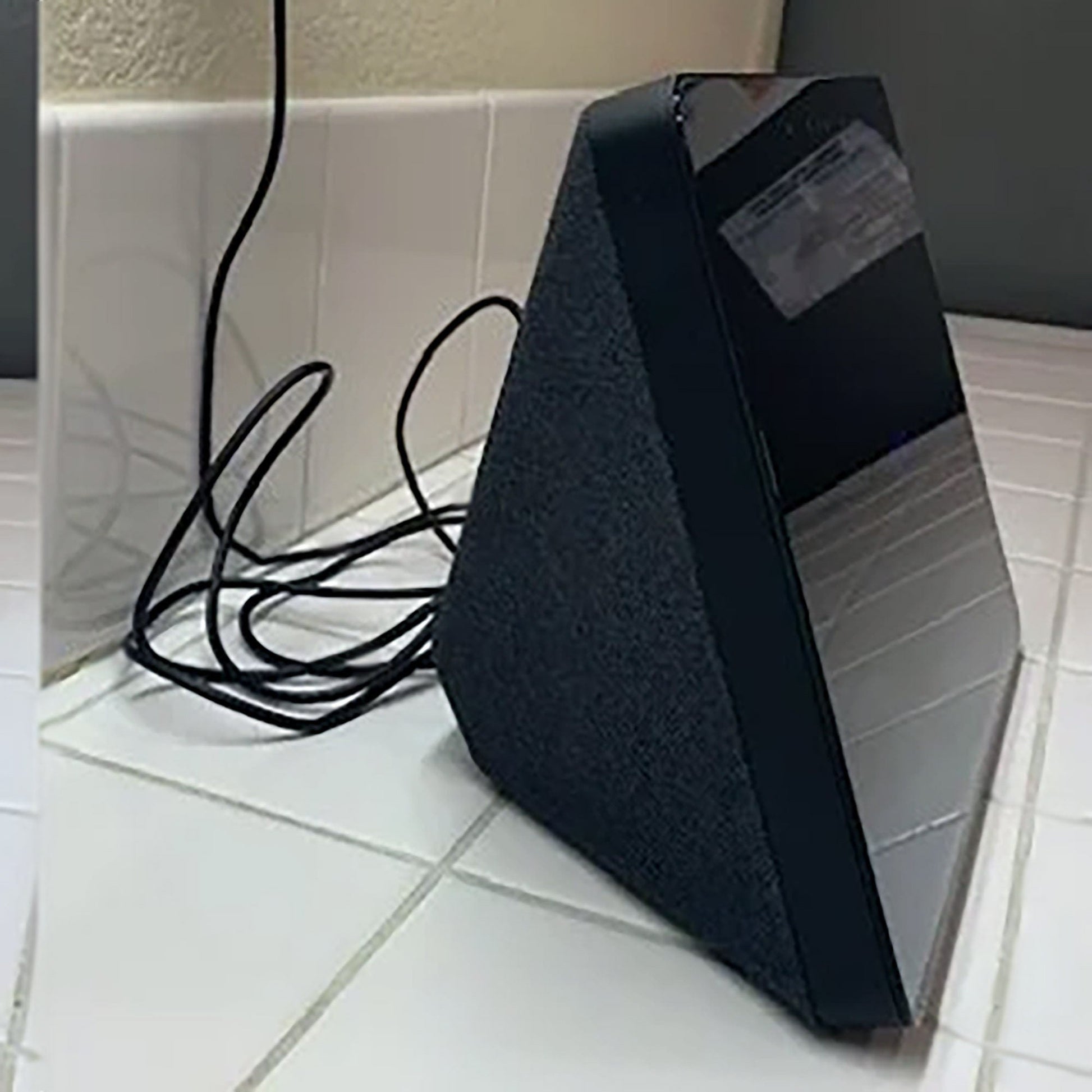 a black speaker sitting on top of a white tiled floor