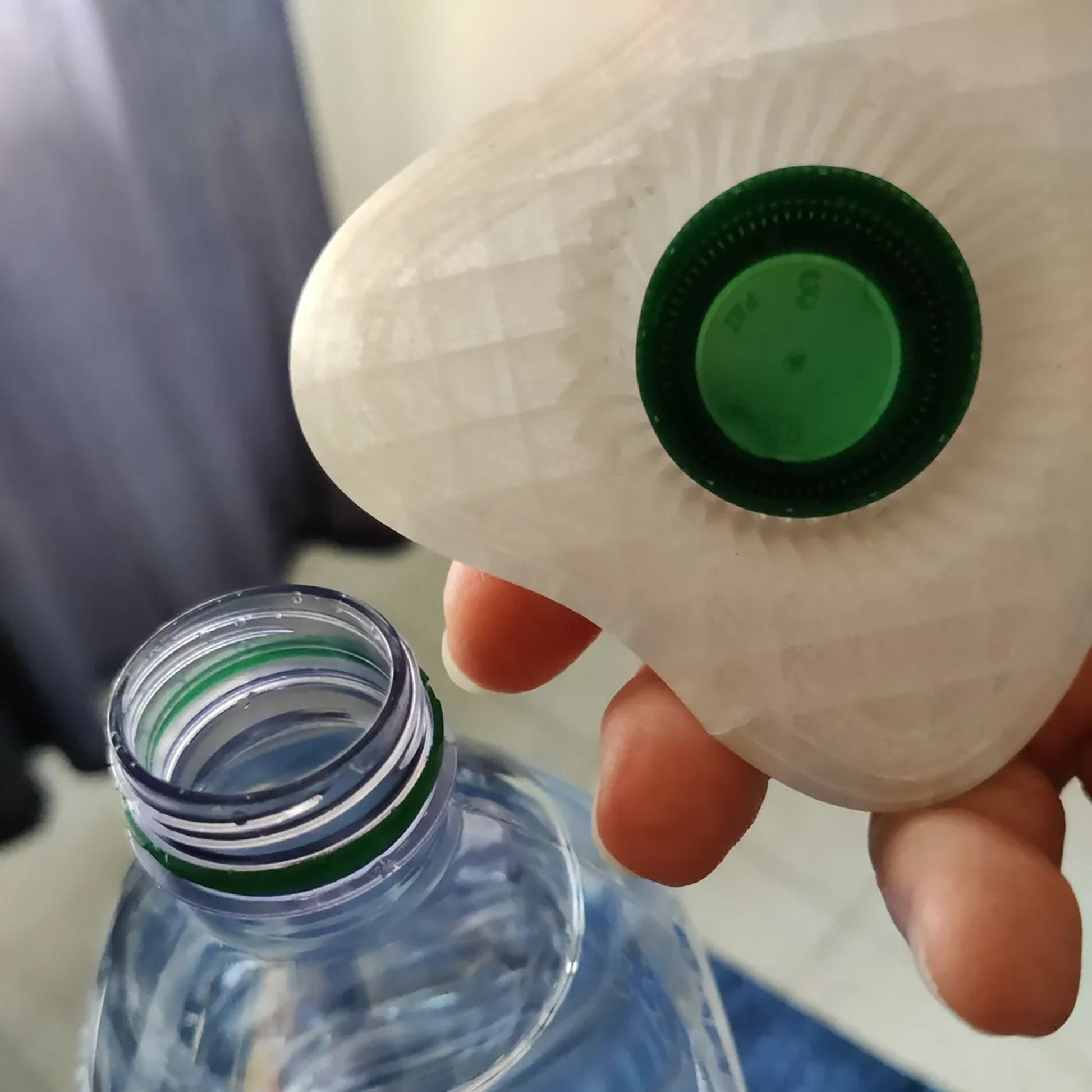 a hand holding a plastic bottle with a green cap