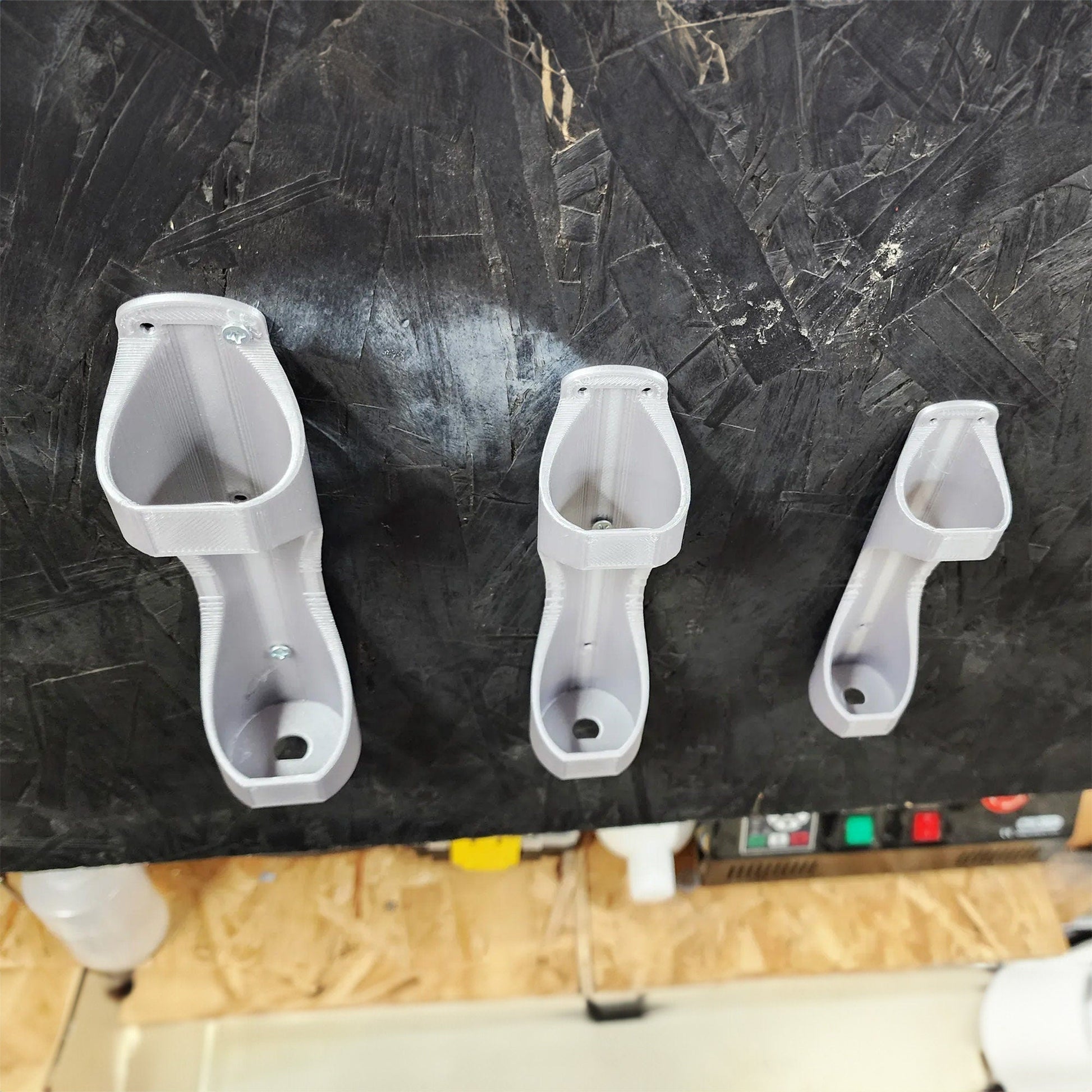 three white urinals mounted to a black wall