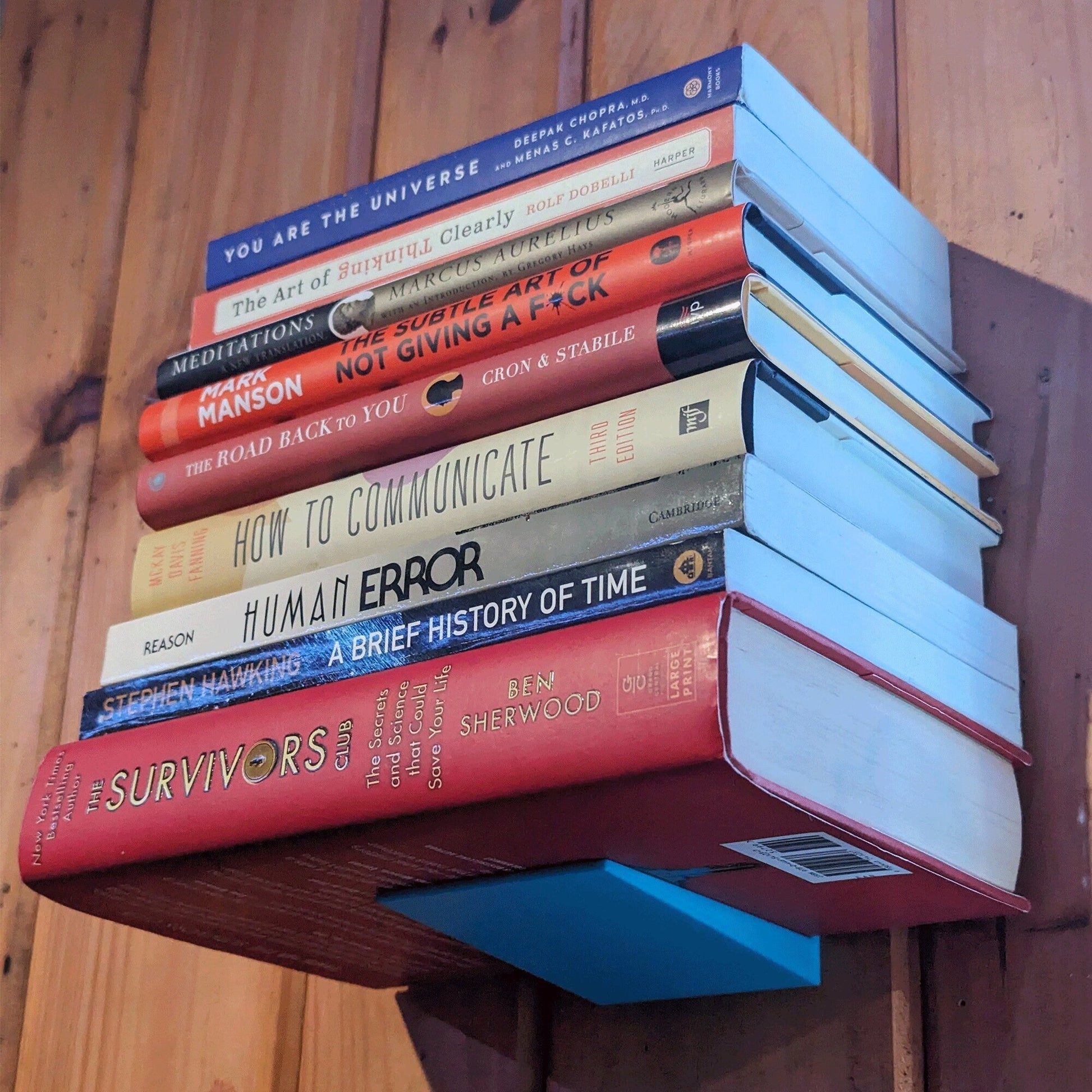 a stack of books sitting on top of a wooden shelf