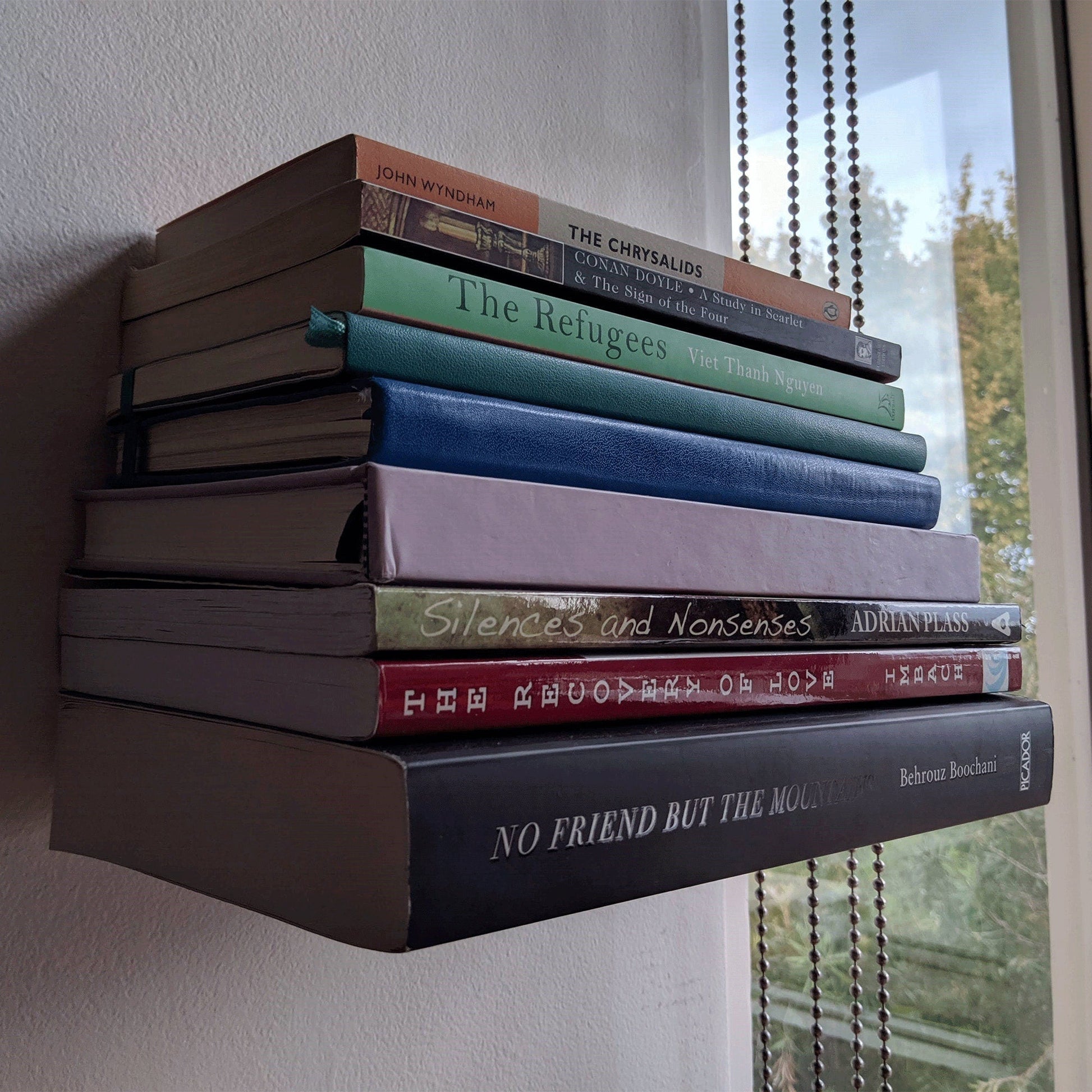 a stack of books sitting on top of a window sill