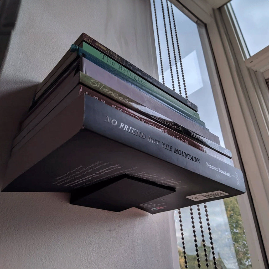 Invisible floating bookshelf bracket holding a stack of books on a wall, view 4