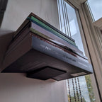 Invisible floating bookshelf bracket holding a stack of books on a wall, view 4