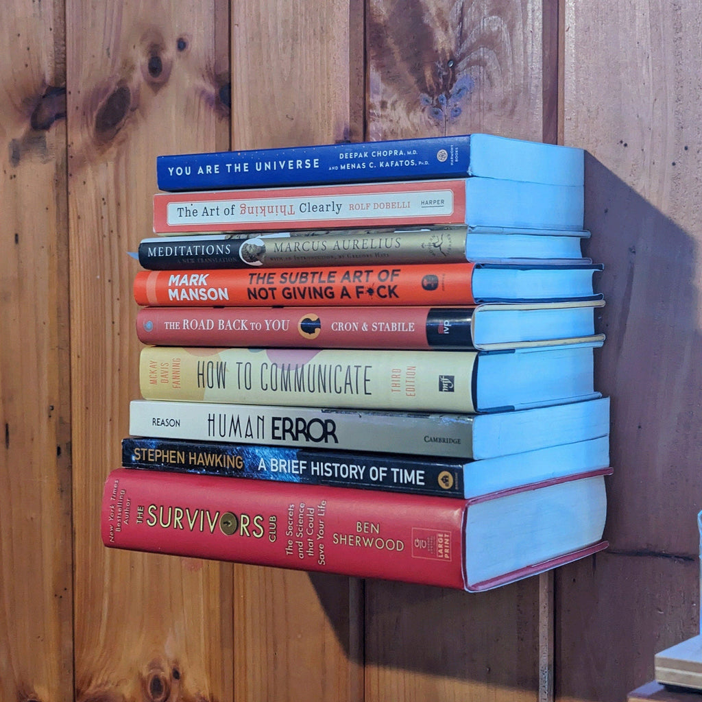 Invisible floating bookshelf bracket holding a stack of books on a wall