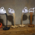 Floating coffee mug sculpture with a coffee stream pouring into a splash puddle, view 2