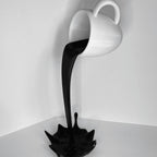Floating coffee mug sculpture with a coffee stream pouring into a splash puddle, view 3