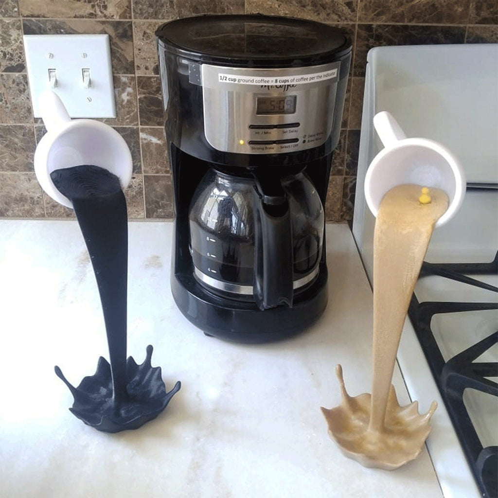 Floating coffee mug sculpture with a coffee stream pouring into a splash puddle