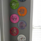 Frisbee wall mount hanger holding an Ultimate disc flat against the wall