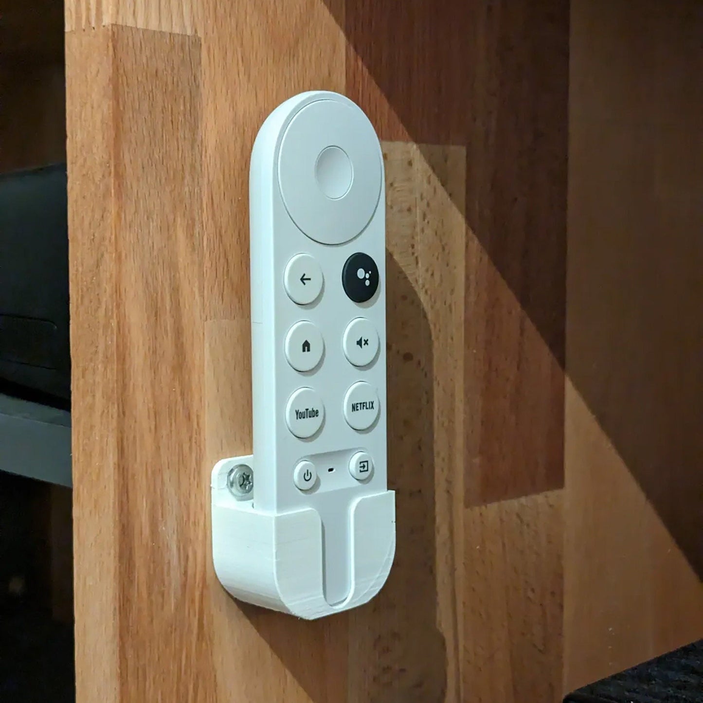 a white remote control attached to a wooden wall