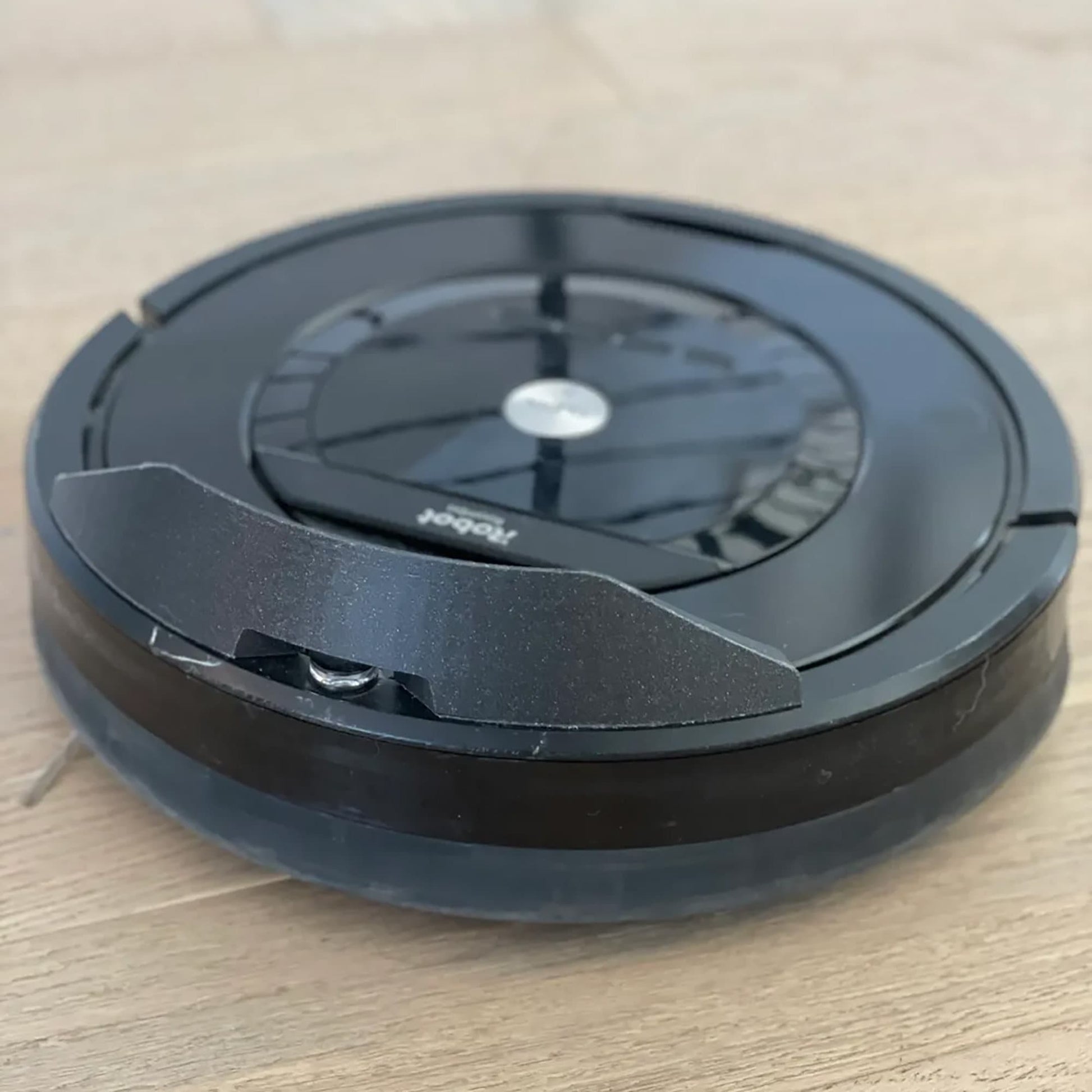 a black robot vacuum sitting on top of a wooden table