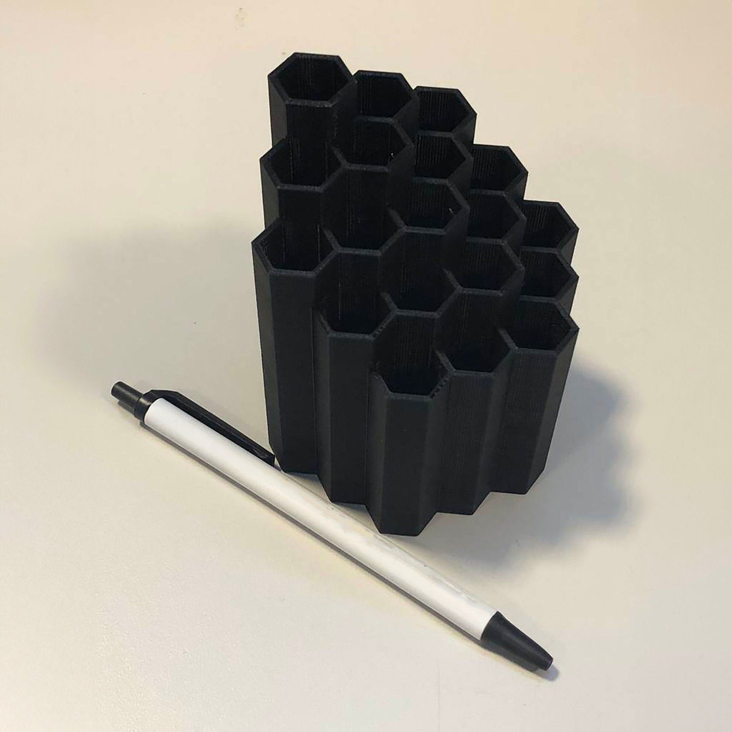 a pen sitting next to a set of black cups