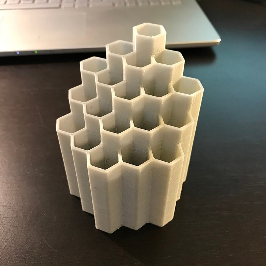 Honeycomb pen and pencil holder with hexagon slots on a desk, view 3