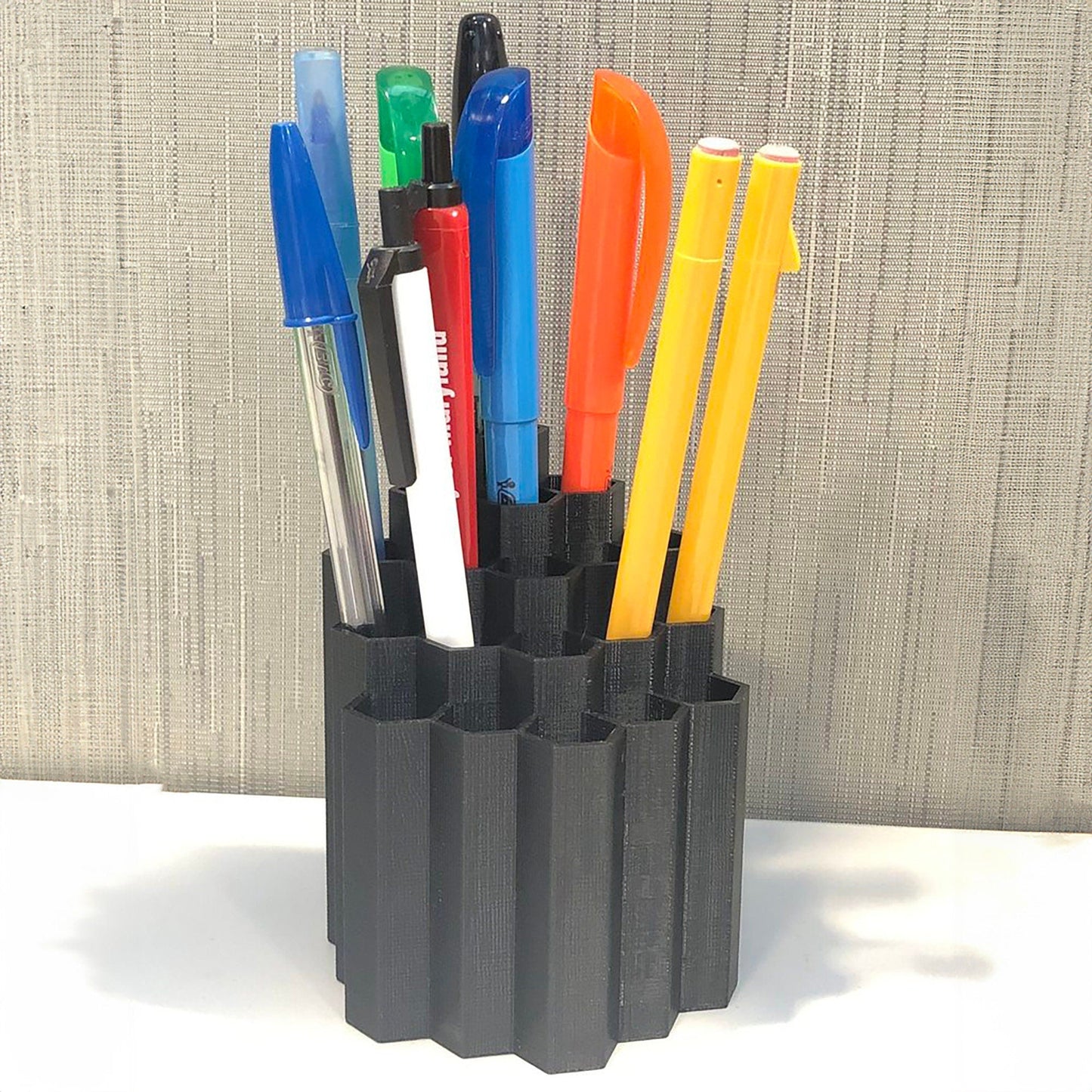 a pen holder with pens and markers in it