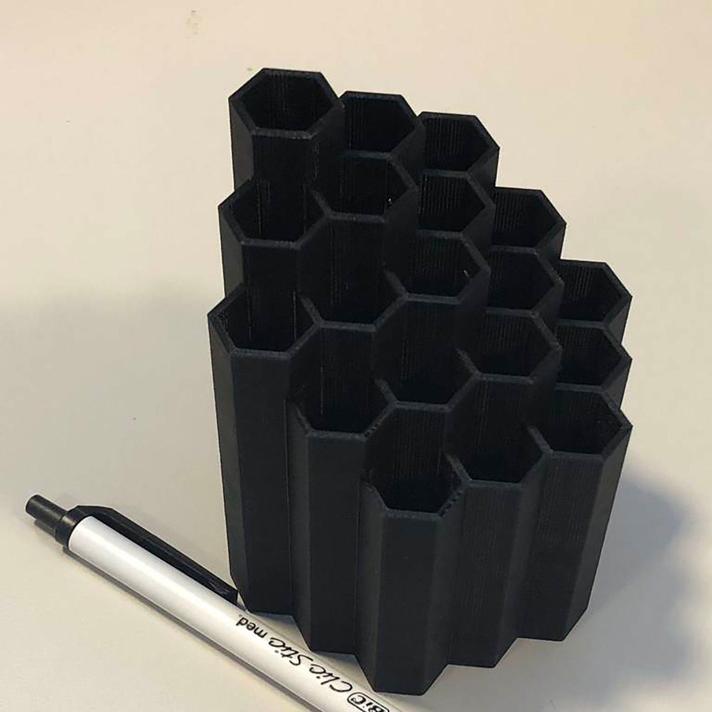 a pen sitting next to a stack of black cups