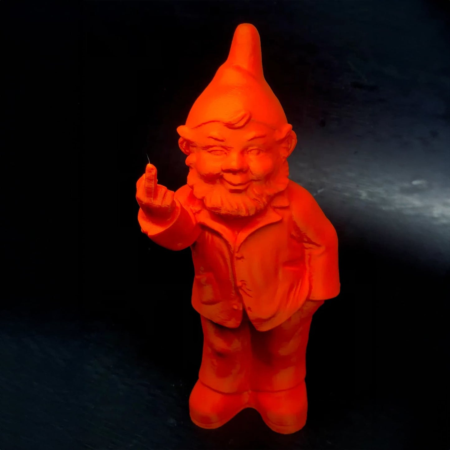 an orange plastic gnome figurine on a black background