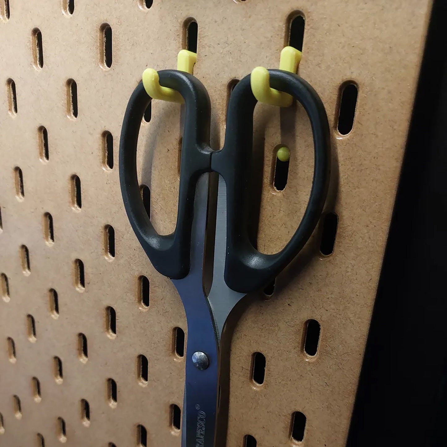 a pair of scissors hanging on a pegboard