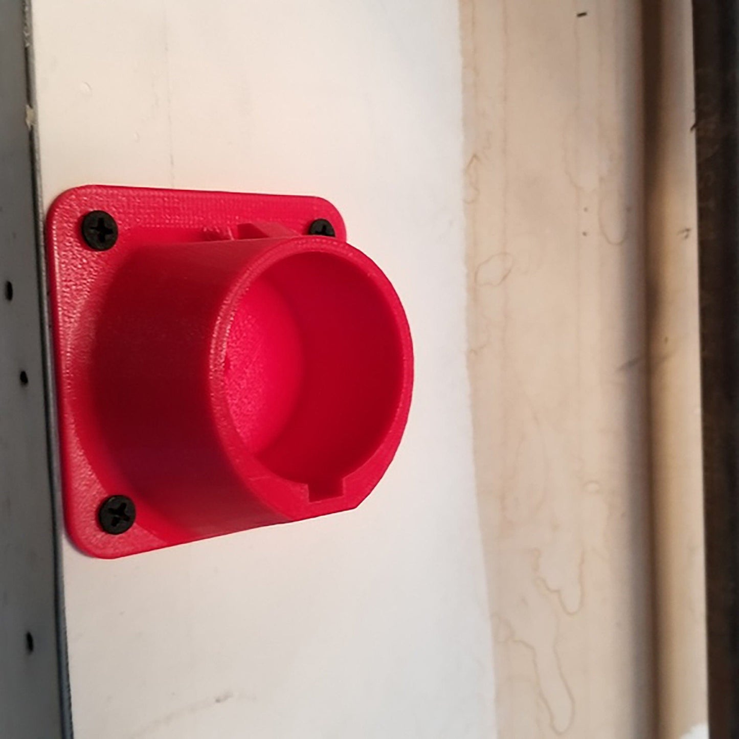 a red plastic object on a white wall