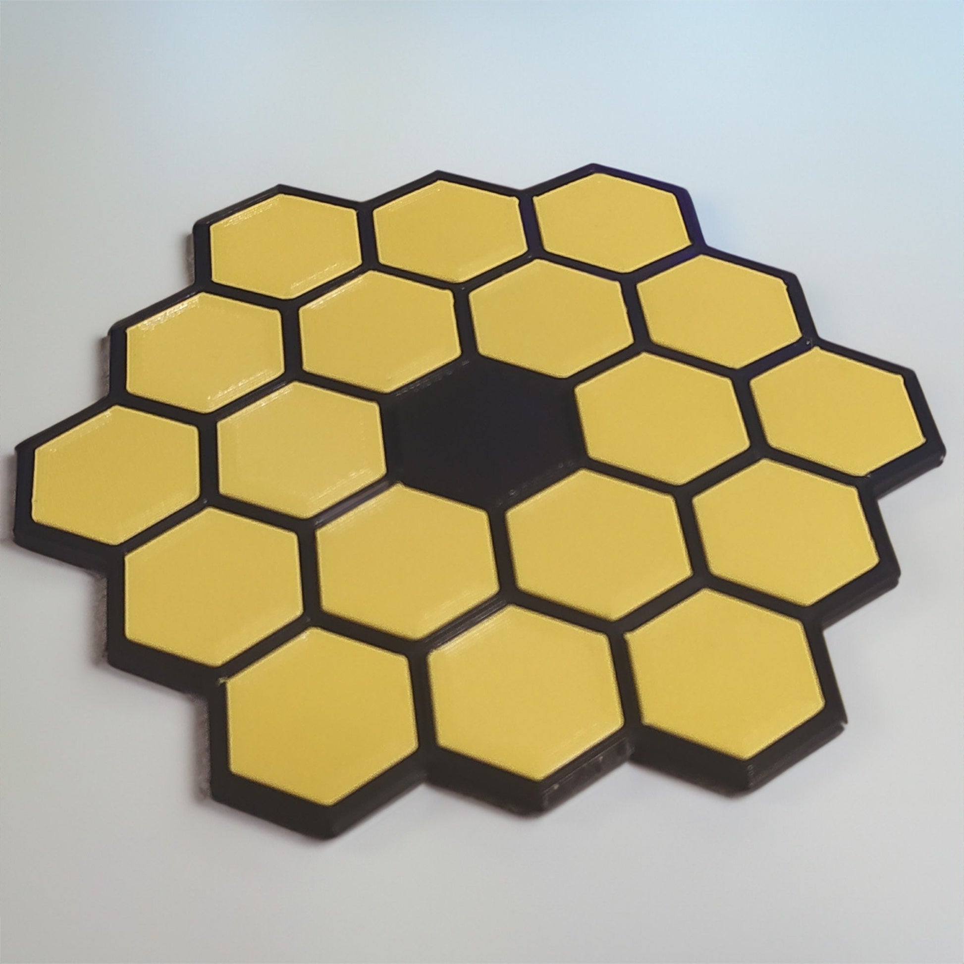 a yellow and black hexagonal object on a white surface