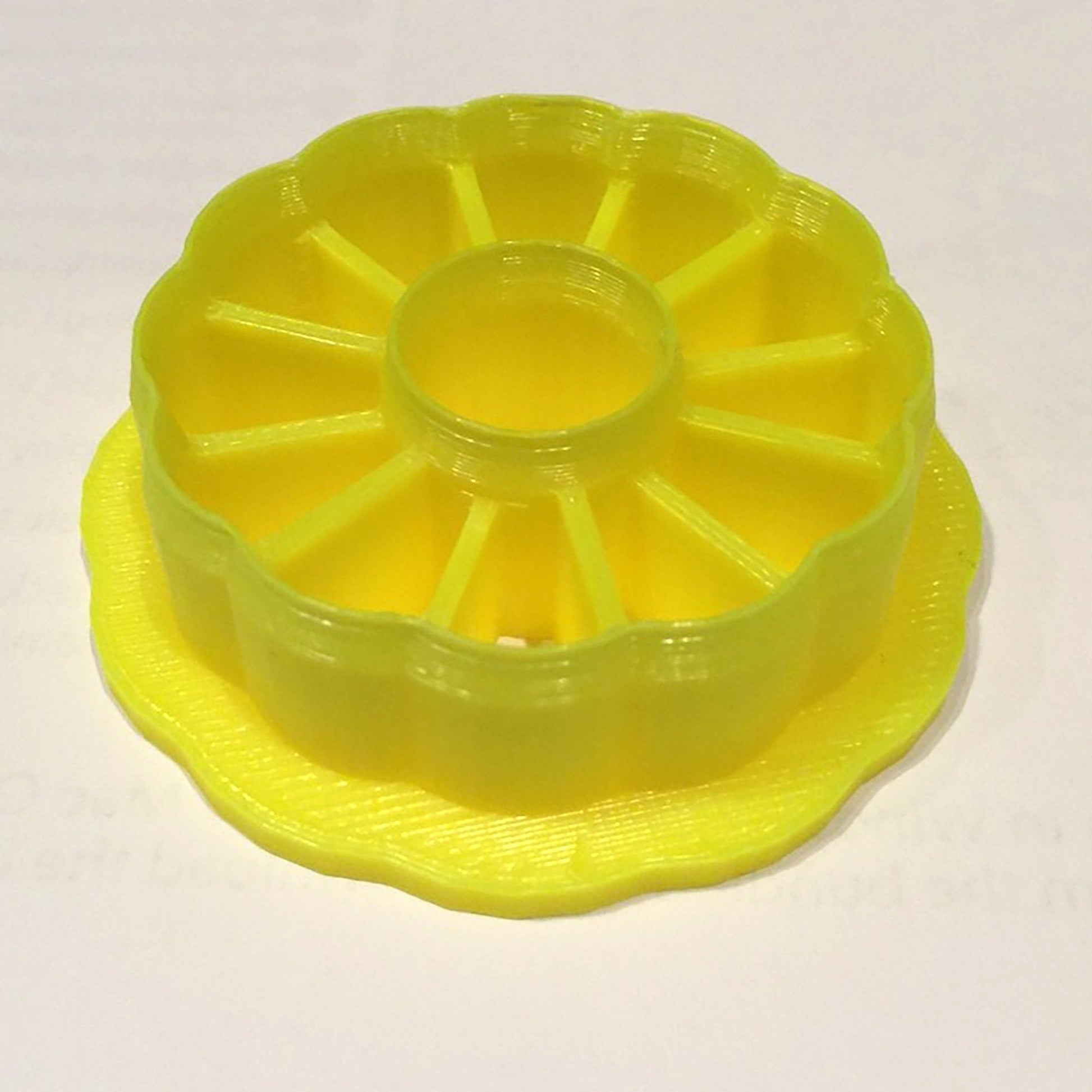 a yellow plastic cake plate with a ring on top of it